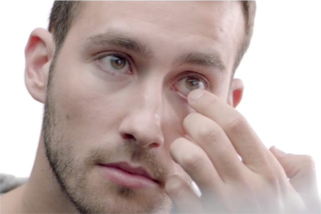 Man putting contact lens into his eye